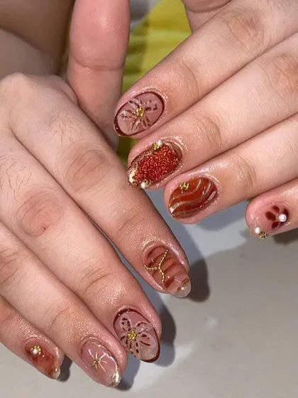 An autumn-inspired set with warm brown tones, glitter, and delicate gold floral and swirl patterns. This shows how to create beautiful seasonal designs.