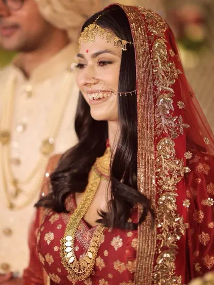 A close-up of a bride's radiant smile, framed by her custom dabka dupatta. The delicate handwork, featuring sitara and tila, was designed to catch the light beautifully.