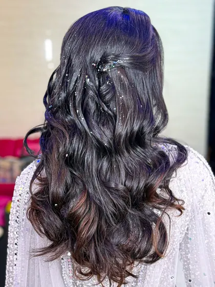 A glamorous sangeet hairstyle with soft waves and scattered glitter for a touch of sparkle.