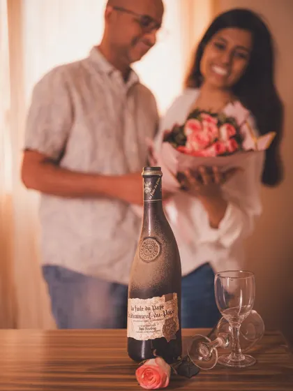 A lifestyle shot featuring a couple in the background, with the wine bottle as the focal point, telling a story of shared romantic moments.