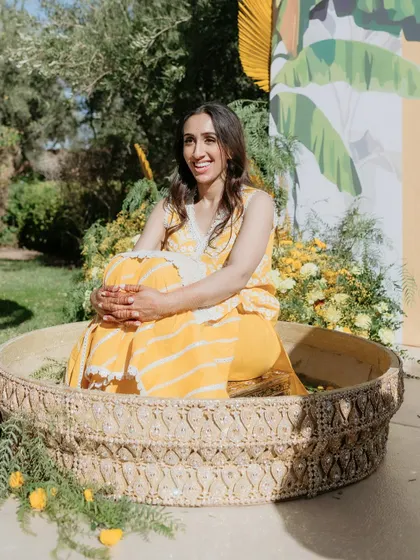 The bride seated in a large, custom-made wicker basket for her Haldi ceremony, surrounded by marigolds.