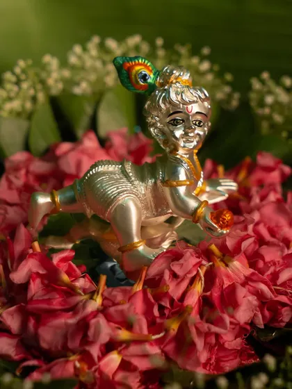 A little Kanha for your mandir, a lot of divinity for your heart. This charming silver Bal Krishna (baby Krishna) idol, resting on a bed of flowers, is a symbol of divine joy and innocence.