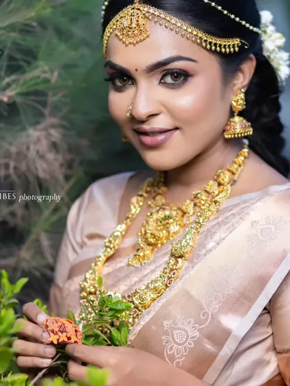 A beautiful outdoor shot of a model in a traditional look. The natural light highlights the dewy finish of the makeup and the intricate jewelry.