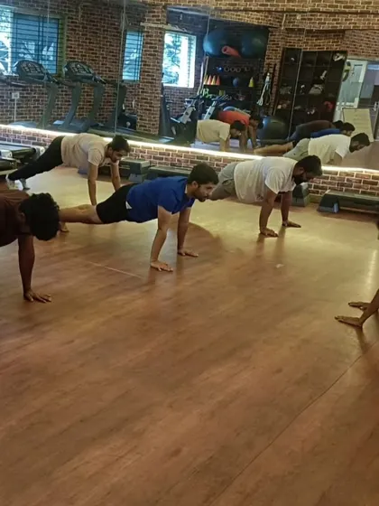 The group transitions into a plank pose, a foundational yoga posture for building core and upper body strength.