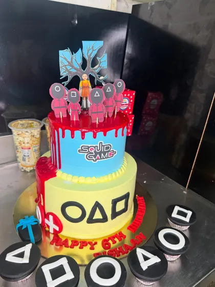 This two-tier Squid Game cake was a unique request for a 6th birthday. It includes iconic symbols from the show and matching cupcakes, showcasing my ability to create cakes based on popular trends.