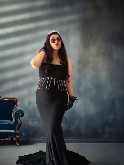 Queen of her castle. This portrait combines glamour and attitude, with a tiara, sunglasses, and a sassy pose against a moody, elegant backdrop.