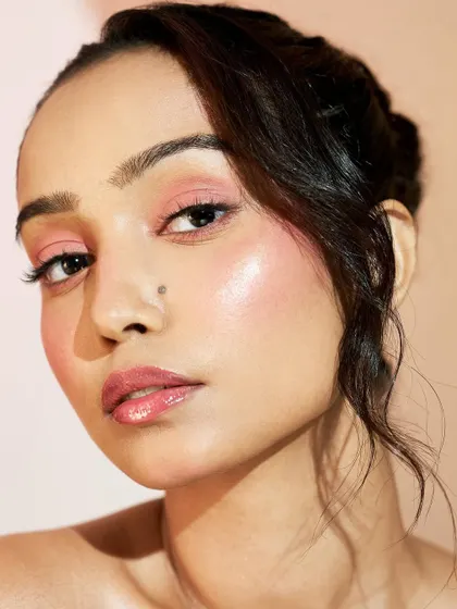 The glossy lip complements the dewy skin, creating a cohesive and luminous final look.