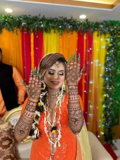 A happy bride showing her back hand mehndi during her ceremony. The design features a mix of net patterns and bold paisley motifs, creating a stunning visual effect.