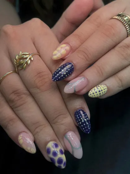 I love playing with different colors and patterns. This festive set features a mix of yellow and dark blue nails with various hand-painted designs like polka dots and floral patterns.