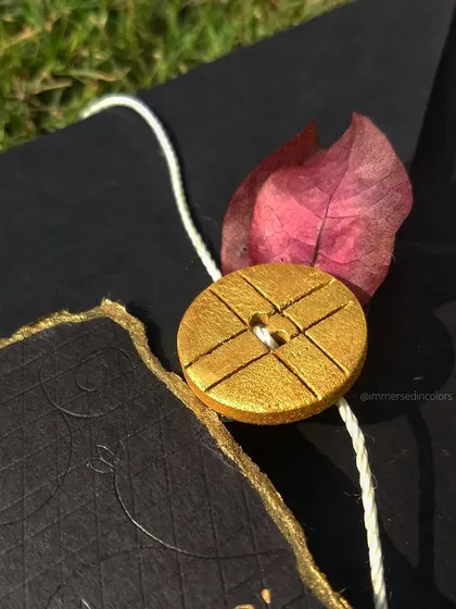 A close-up detail of the gold-painted button and deckled, gold-leafed edge of a custom letter. These small touches make each piece unique.