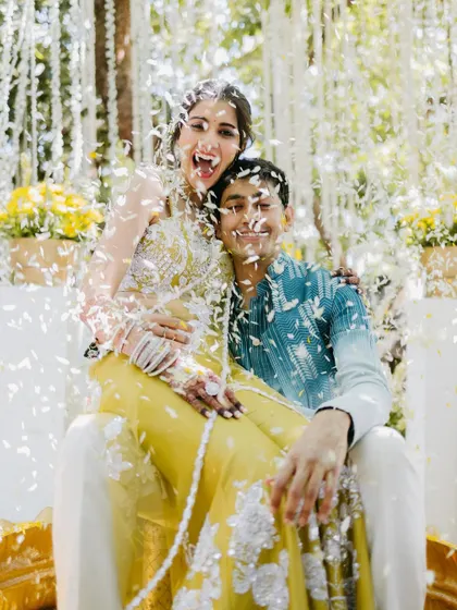 A fun and candid moment where the bride playfully pretends to bite the groom while being showered with petals during their Haldi.