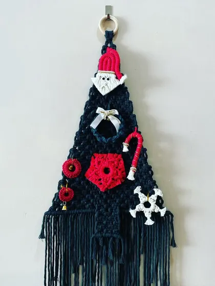 My macrame Christmas tree wall hanging is a unique take on holiday decor. It's adorned with a little Santa, a candy cane, a wreath, and other festive ornaments, all made from macrame.