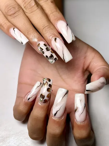 A modern and edgy design. This set features a white marble base with black lines and a bold leopard print accent nail with gold details.