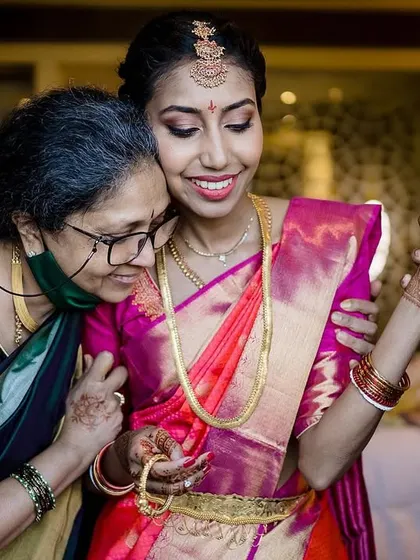 A heartwarming scene of a bride getting ready with the help of her mother and another family member. Their smiles and gentle touches show the love and support surrounding her.