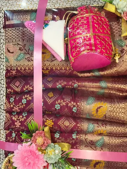 A stack of sarees packed in a tray, with a matching potli bag on top.