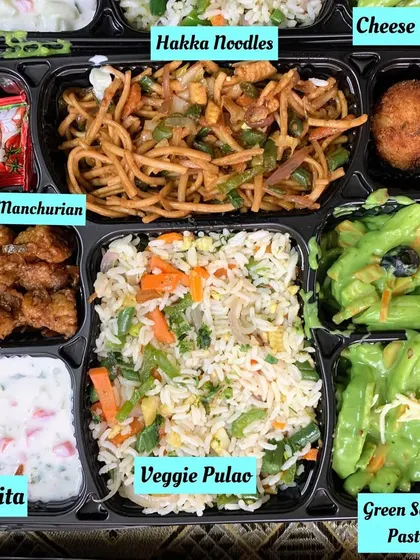 An Indo Chinese fusion meal tray for a change of pace. This box contains Green Sauce Pasta, Veg Hakka Noodles, Veggie Pulao, Babycorn Manchurian, a cheese ball, and raita.