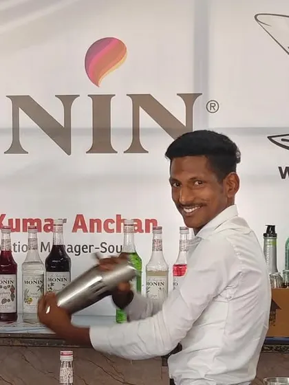 A student smiles while practicing his shaking technique in front of our Martiny and Monin collaboration banner.