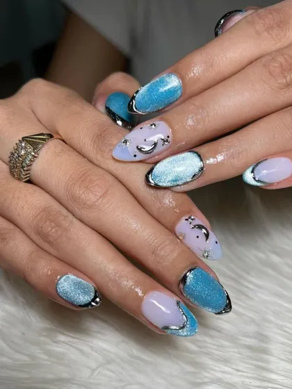 A celestial dream. This set combines a light blue cat-eye effect with lavender nails, all outlined in silver chrome and accented with tiny moon and star details.