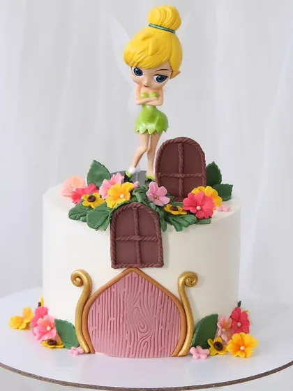 A magical Tinker Bell cake for a fairy-themed party. The design features a fondant fairy house with a wooden door and windows, surrounded by flowers, with Tinker Bell herself on top.
