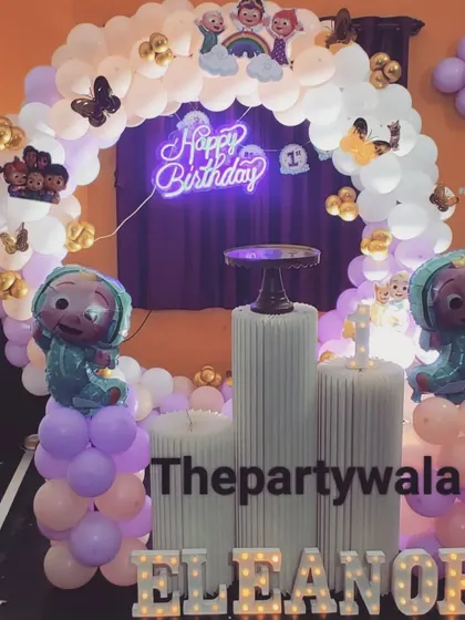 A Cocomelon ring decoration with a 'Happy Birthday' neon sign and character foil balloons.