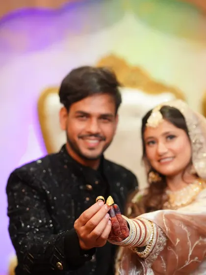 A creative shot focusing on the couple's hands and rings, with their smiling faces blurred softly in the background. This highlights the symbol of their union.