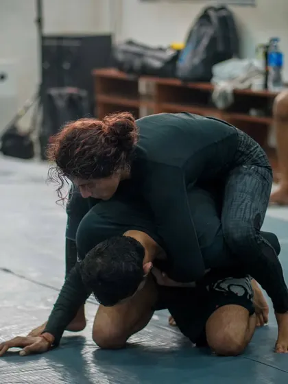 A female practitioner controlling her opponent from the back mount. Our Jiu Jitsu program is for everyone, and we focus on technique over strength.