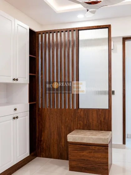 The entryway of the Kolkata project, featuring a beautiful wooden partition with a built-in shoe cabinet and seating, combining style with practicality.