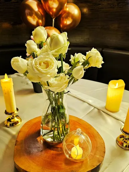 Another angle of the elegant table centerpiece, showing the detail of the white roses and warm, flickering LED candles.