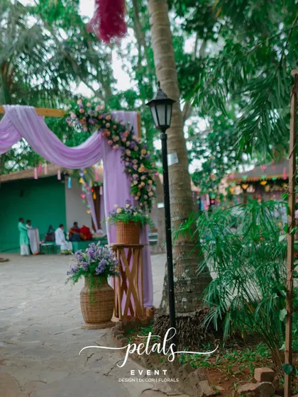 The entrance decor for a pre-wedding event, featuring purple drapes, floral arrangements, and a charming lamp post.