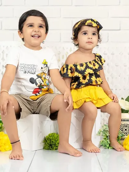 Two siblings, a brother and sister, sit side-by-side in a bright, clean studio setup. A beautiful portrait of their budding friendship.