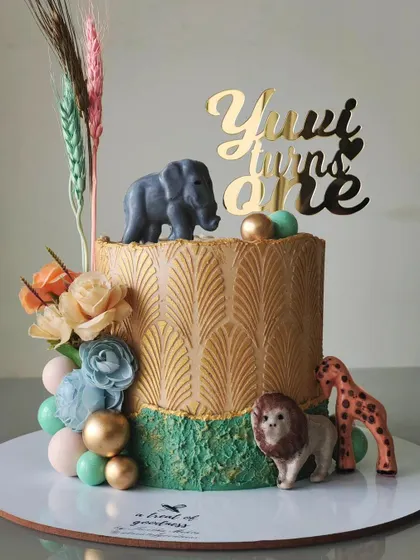 A chic safari-themed cake for a first birthday. I used a gold art-deco stencil and a rustic green texture, then added cute animal figures and dried wheat stalks for a modern, bohemian take on a classic theme.