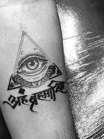 A closer look at the "Aham Brahmasmi" and all-seeing eye tattoo. The clean linework and dotwork shading create a sharp, impactful design.