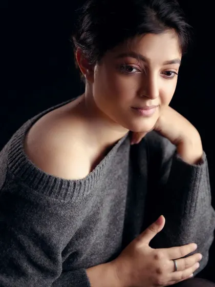 This portrait showcases a pensive and gentle mood. The off-the-shoulder sweater and soft lighting create a feeling of quiet confidence and natural beauty.