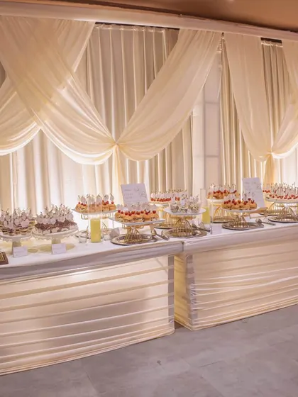 An elegant dessert table with illuminated bases and a backdrop of soft, draped fabric, creating a luxurious and inviting display.