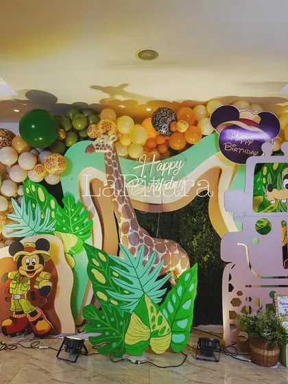 A fun and playful photo backdrop featuring a safari jeep cutout where kids can pose, surrounded by jungle foliage and friendly Disney characters.