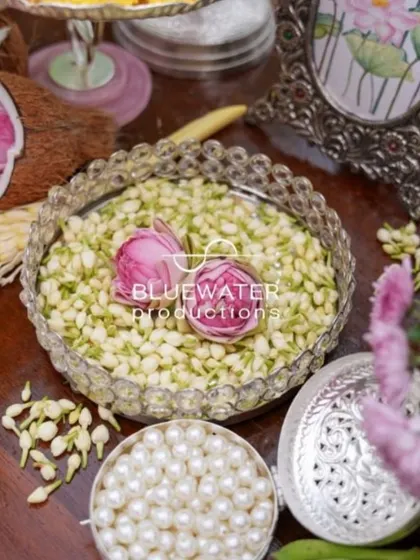 Traditional elements for a Haldi ceremony, including a bowl of jasmine buds, pearls, and a decorative silver box.