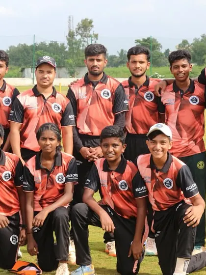 A youth team in their orange and black kits poses for a group photograph.