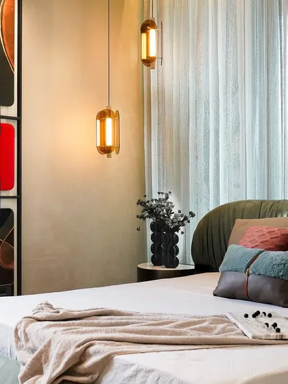 This angle of the master bedroom highlights the warm glow of the pendant lights against the textured wall finishes. The mix of colors and materials creates a rich, layered, and deeply personal space.