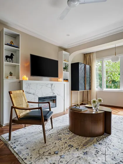 This living room features a modern fireplace clad in marble, flanked by built-in shelving. The design is clean and contemporary, with a focus on natural light.