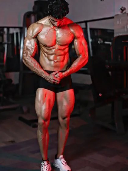 A most muscular pose under red lighting, emphasizing the vascularity and muscle density achieved during a cutting phase.