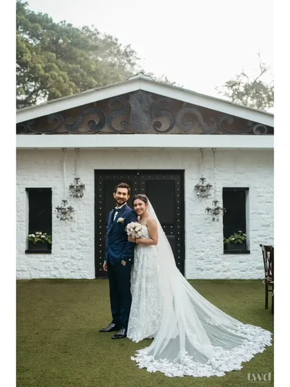 A classic and elegant portrait of the Catholic bride and groom. The bride's long, beautiful veil is spread out, adding a touch of drama and grace to the photograph.