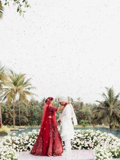 The varmala exchange with a backdrop of palm trees and white florals. A perfect blend of tropical and elegant.