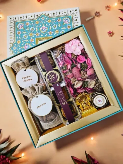 This hamper combines health and tradition with potlis of almonds and peri-peri cashews, Smoor baklava, a Ganesha idol, and fragrant potpourri, all in a beautiful turquoise box.