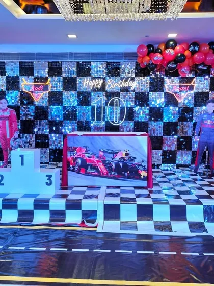 The full F1 racing theme setup, complete with a race track floor, checkered flag details, and a large chandelier adding a touch of class.