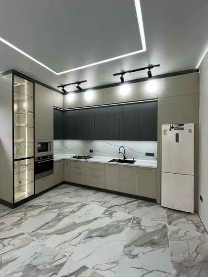 A wide shot of the dual-tone kitchen, showing the marble-look floor tiles and the overall spacious layout.
