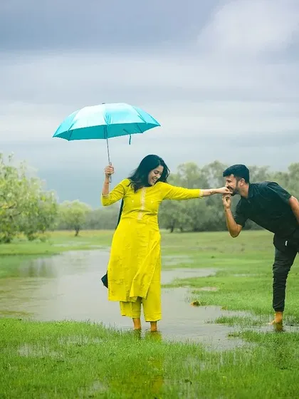 A playful pre-wedding moment in a rain-soaked field. The bright yellow of her outfit and the blue umbrella add a pop of color to the moody, natural landscape, showing how I work with any weather condition.