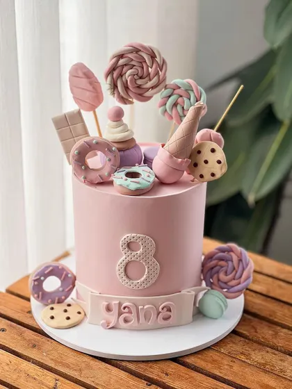 A fun and colorful candy-themed cake for an 8th birthday, loaded with edible donuts, cookies, and lollipops.