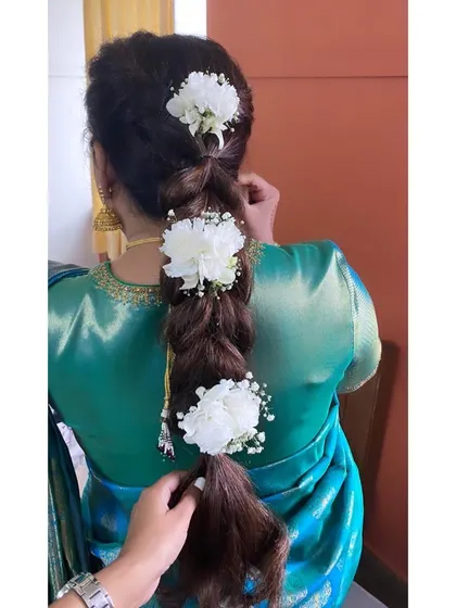 A simple, textured braid decorated with large, fresh white flowers. This is a great example of how fresh flowers can elevate a simple hairstyle.