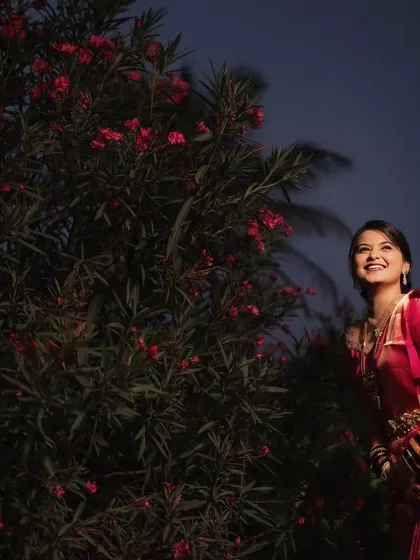 A joyful, upward glance from the bride, standing next to a flowering bush at dusk. Her happiness is the highlight of this beautiful, candid portrait.