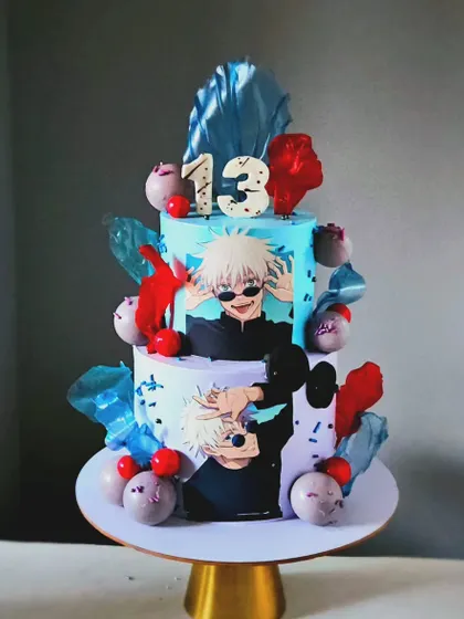 A stylish Gojo theme cake for a 13th birthday. This two-tier anime cake is decorated with rice paper sails and character prints for a modern, cool look.